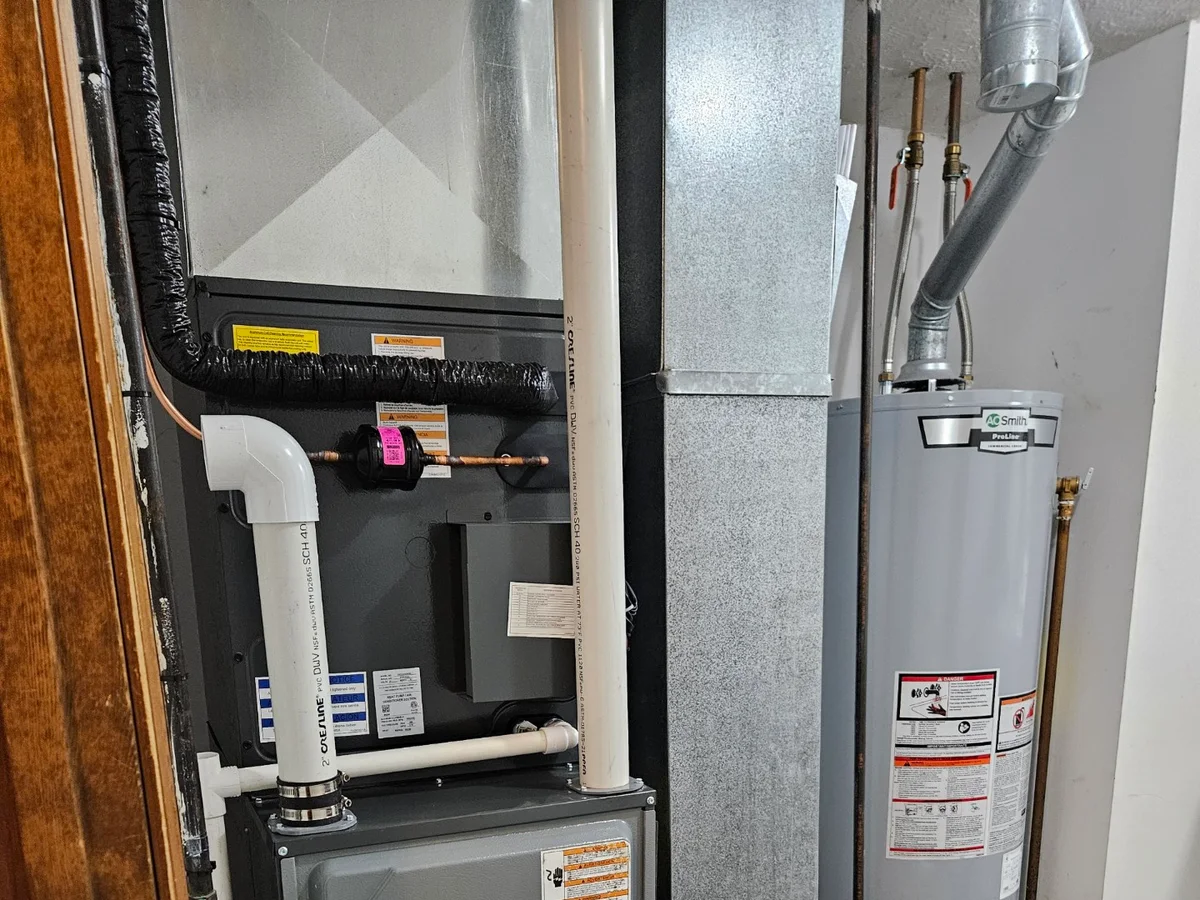 Finished indoor heating system and water heater installation inside a utility room.