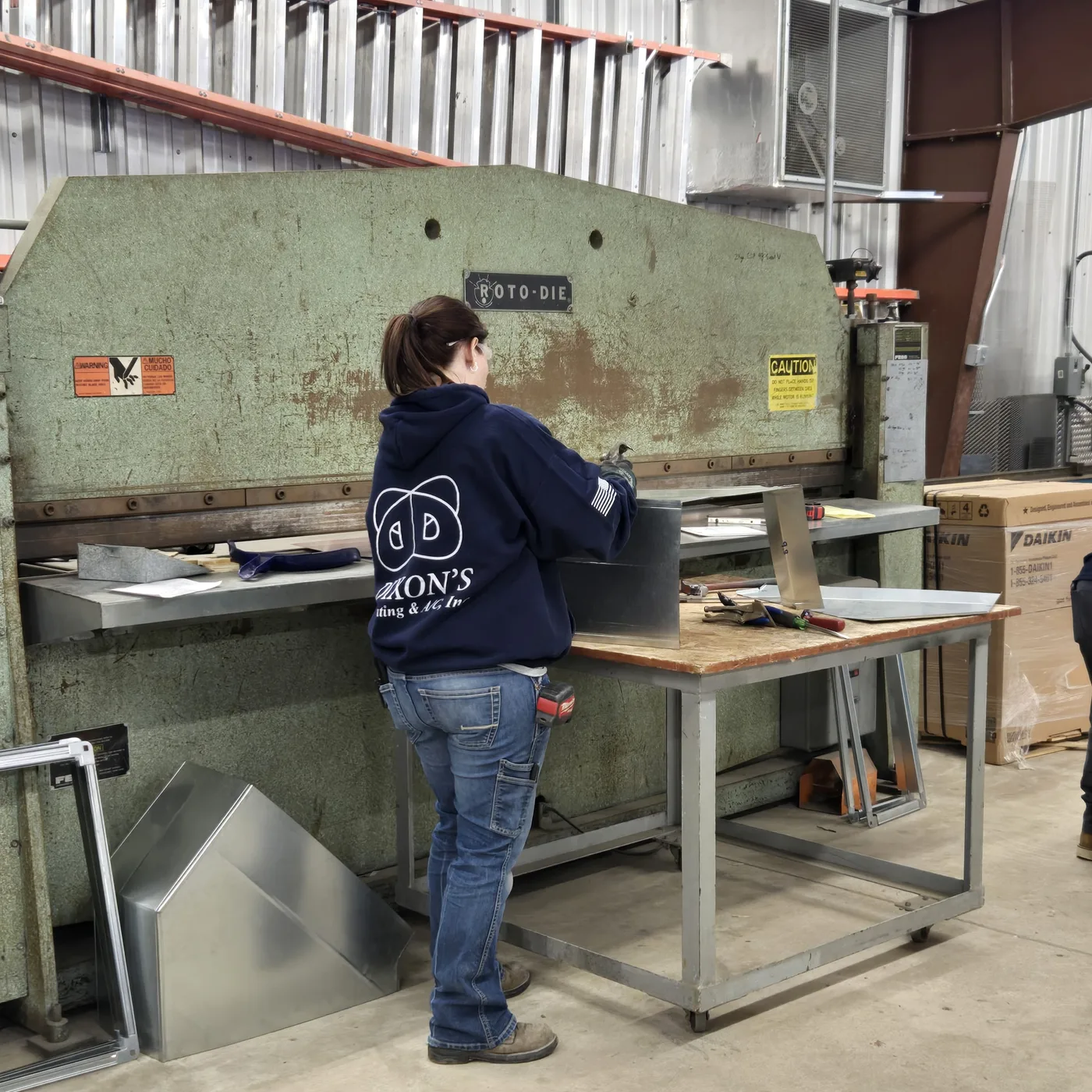 Dixon's technician in a navy hoodie forming a duct at the Roto-Die brake