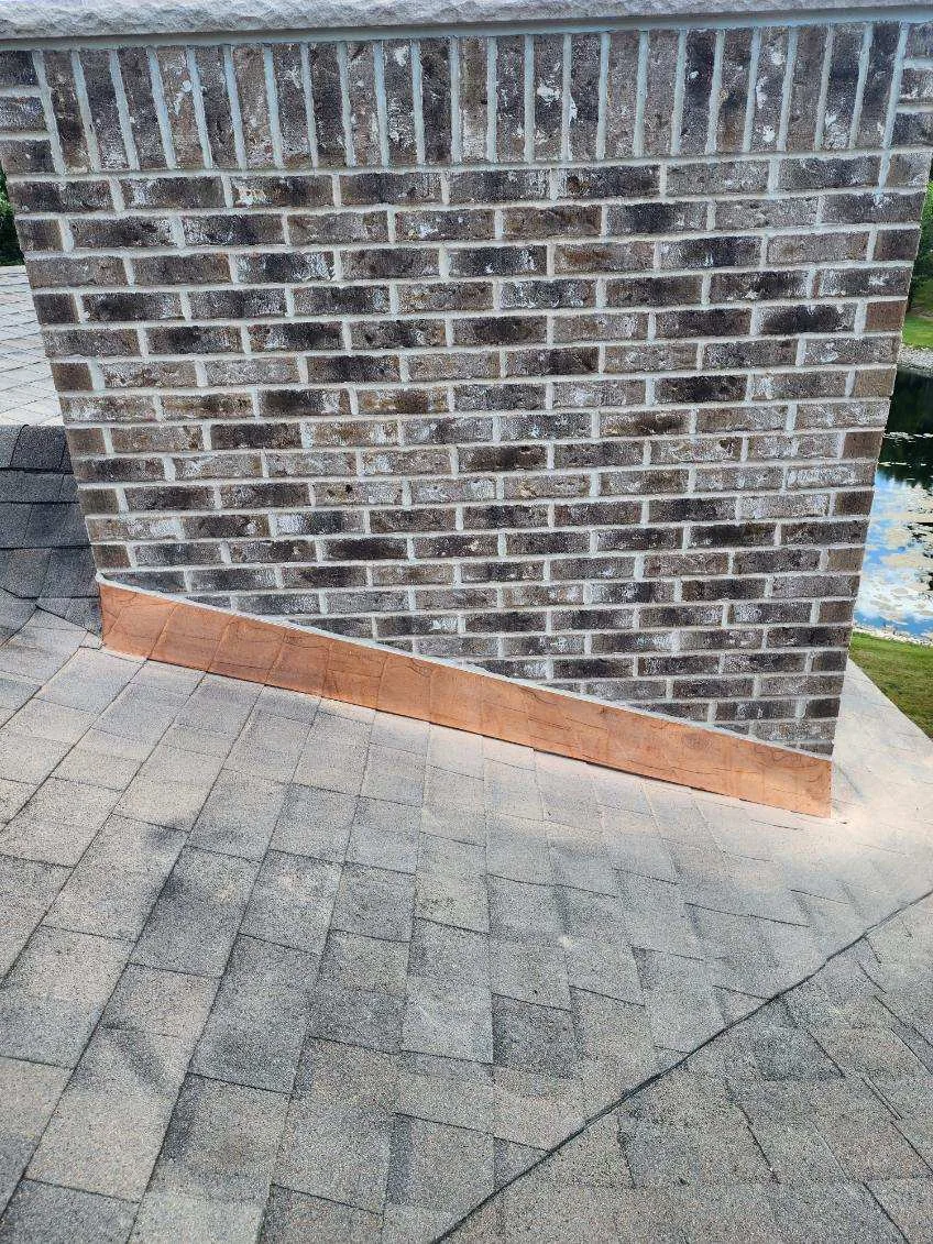 Hand-formed copper chimney flashing tucked along a brick chimney