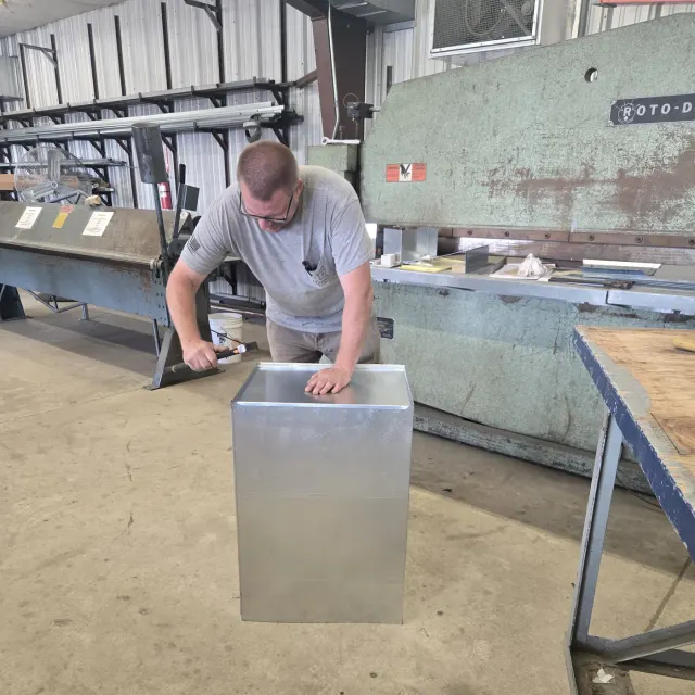 Dixon's technician tapping the seams on a newly formed sheet-metal plenum next to the Roto-Die brake