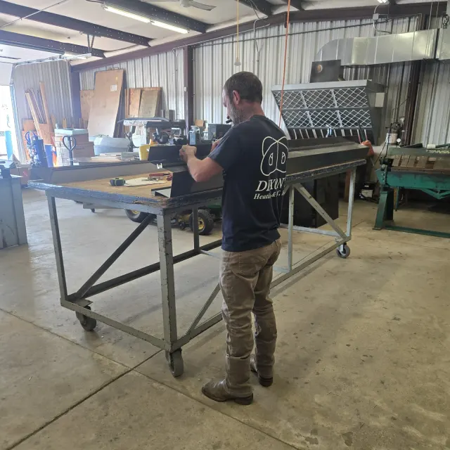 Two Dixon's technicians operating the Roto-Die sheet-metal brake in the fabrication shop