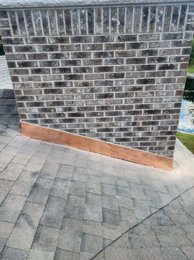 Hand-formed copper chimney flashing tucked along a brick chimney